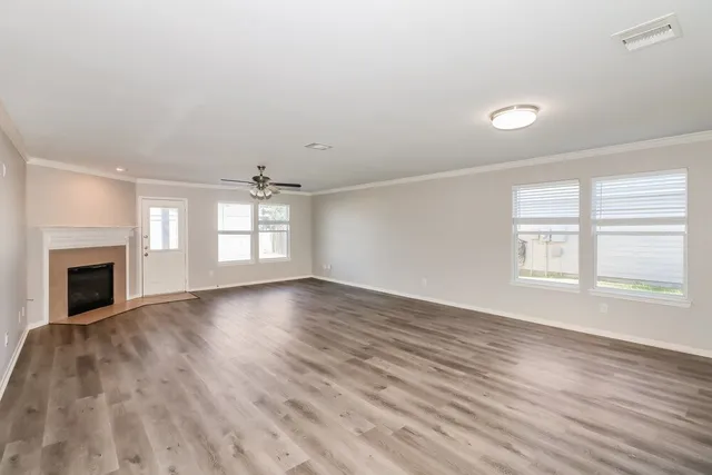 an empty room with wooden floor fireplace and windows