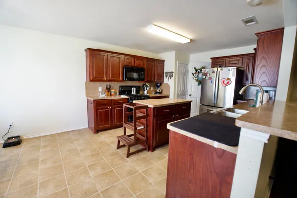 a view of kitchen with stainless steel appliances granite countertop sink stove top oven and cabinets