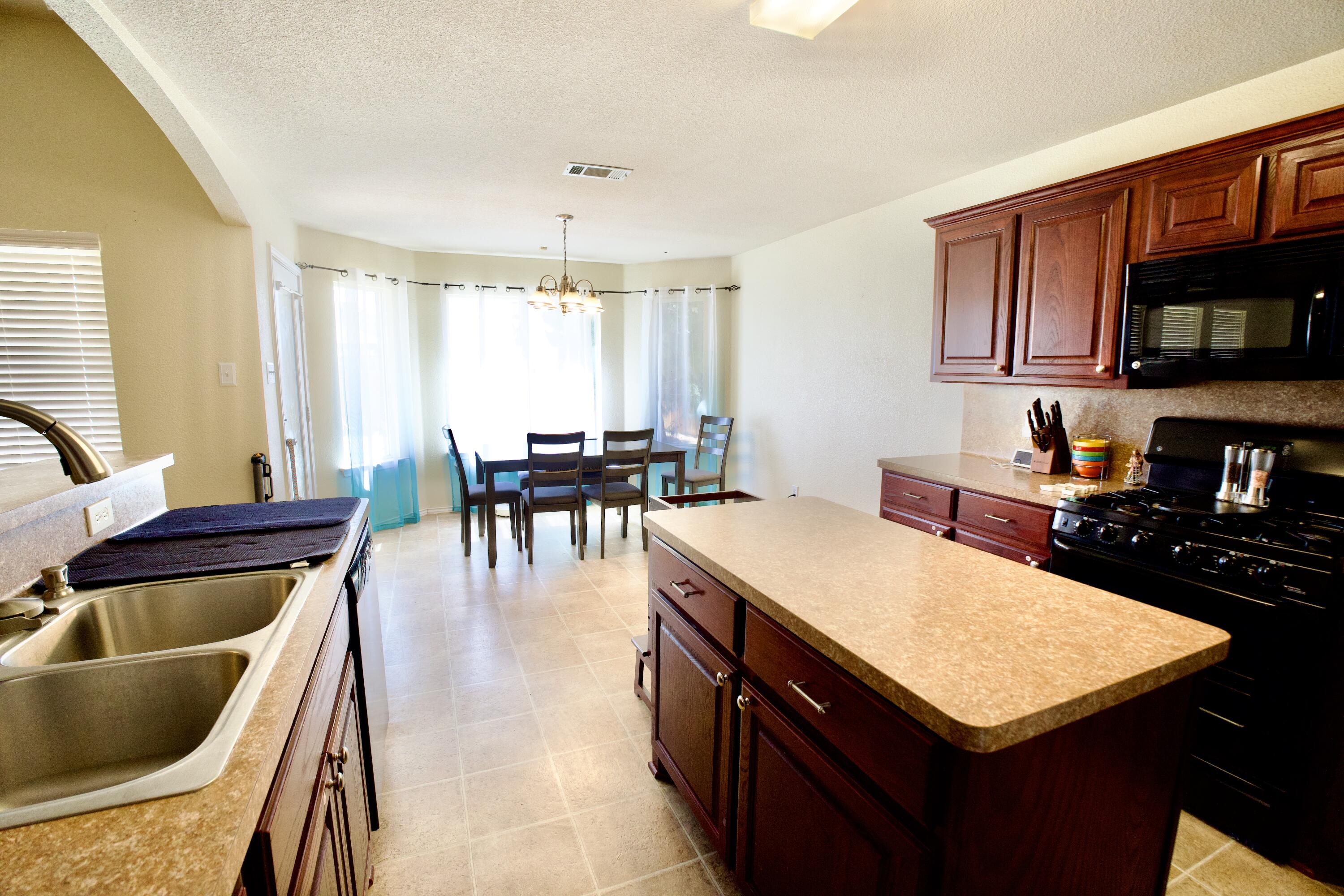 8811 16th Street Lubbock, TX 79416 - Photo 14 of 17 a kitchen with a sink a stove and chairs