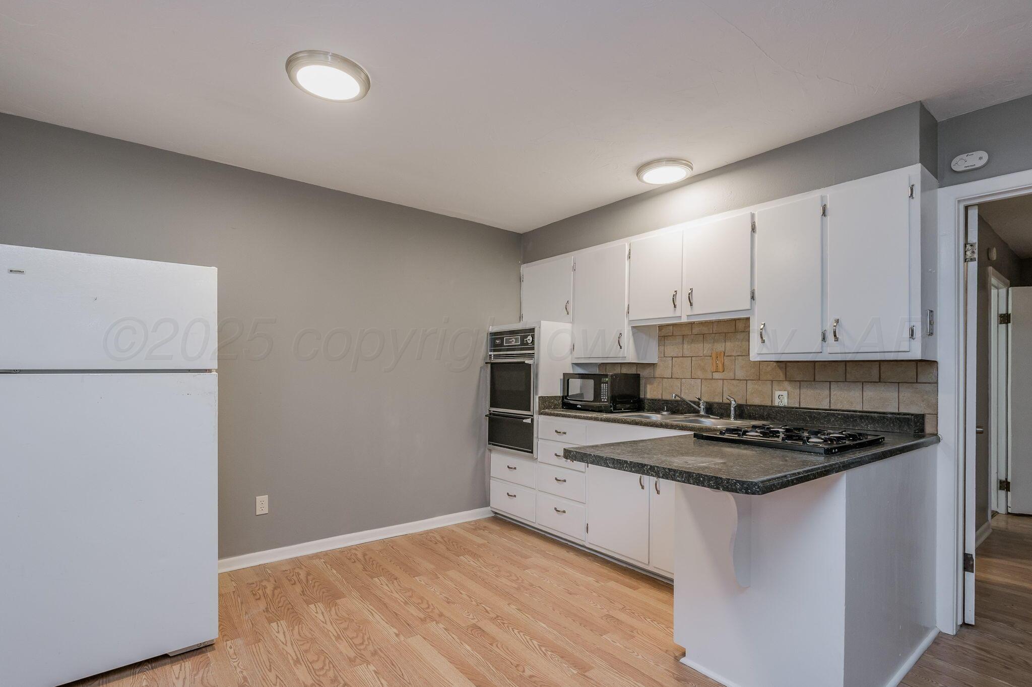 609 16th Street, Unit 3 Canyon, TX 79015 - Photo 7 of 15 a kitchen with stainless steel appliances a refrigerator a stove a sink and white cabinets