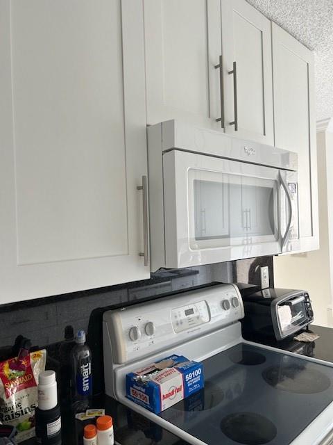 3590 Blue Lake Drive, Unit 305 Pompano Beach, FL 33064 - Photo 14 of 23 a kitchen with white cabinets and black appliances