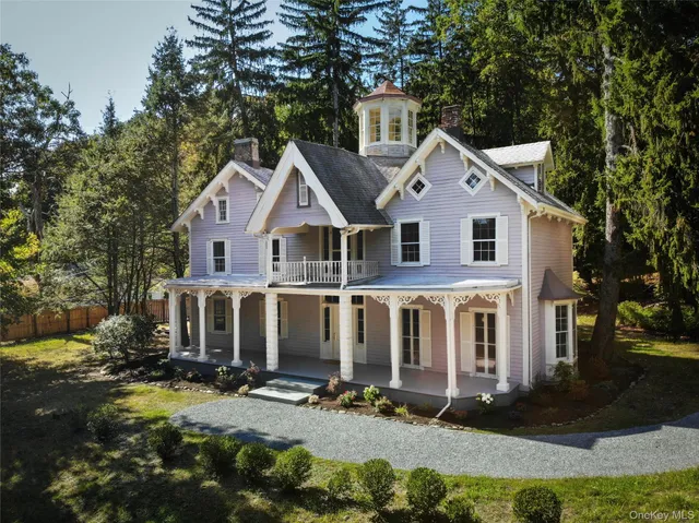 a view of a white house next to a yard with big trees