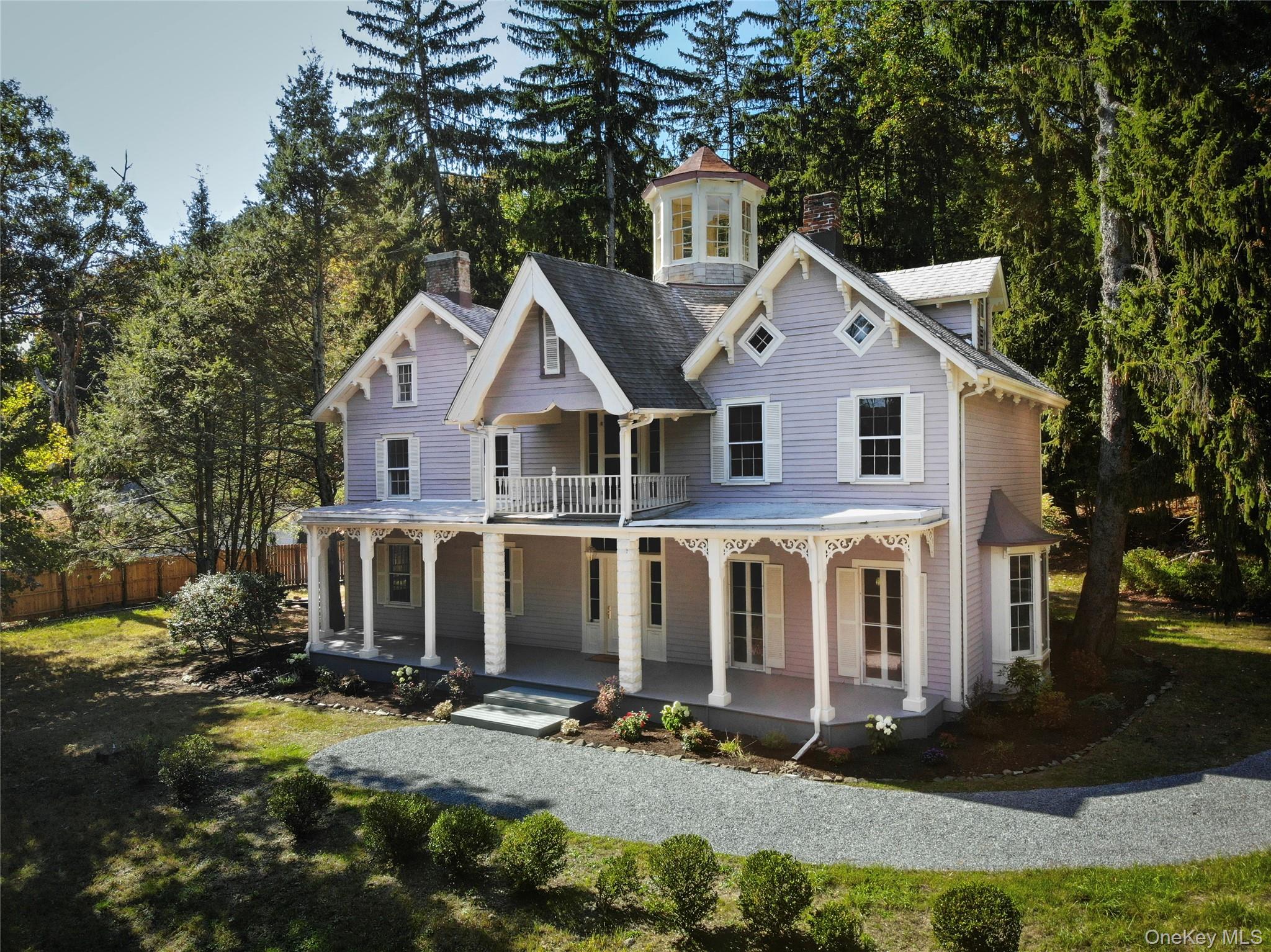 a view of a white house next to a yard with big trees
