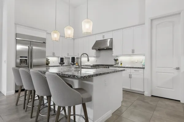 a kitchen with stainless steel appliances granite countertop a sink a stove a refrigerator and island with wooden floor