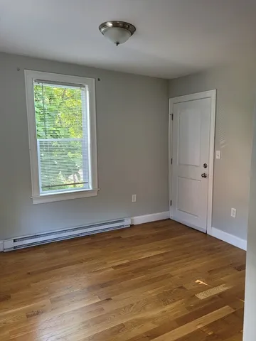 a view of an empty room with wooden floor and a window