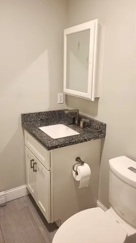 a bathroom with a granite countertop toilet sink and mirror