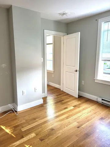 a view of an empty room with window and wooden floor