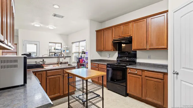 a kitchen with stainless steel appliances granite countertop a stove top oven a sink dishwasher and cabinets with wooden floor