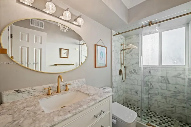 a bathroom with a granite countertop sink a toilet and shower