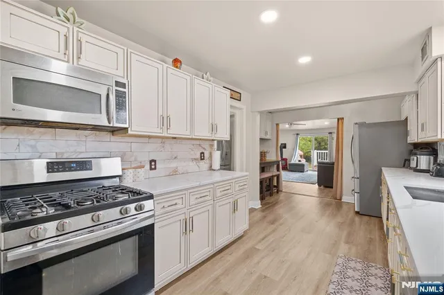 a kitchen with stainless steel appliances white cabinets and stove top oven