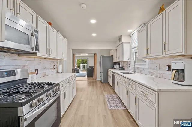 a large kitchen with stainless steel appliances granite countertop a stove a sink dishwasher and a refrigerator