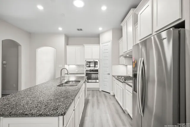 a kitchen with stainless steel appliances granite countertop a refrigerator and a sink