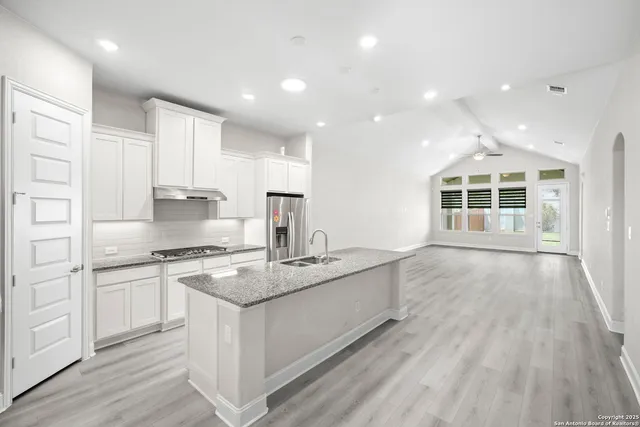 a large kitchen with stainless steel appliances granite countertop a lot of counter space and wooden floors