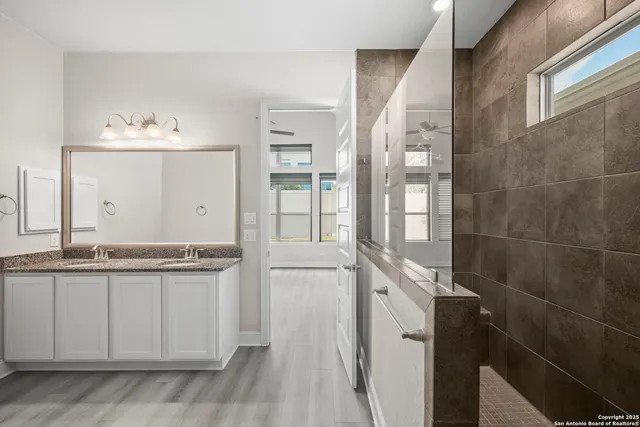 a bathroom with a granite countertop sink a mirror and a shower