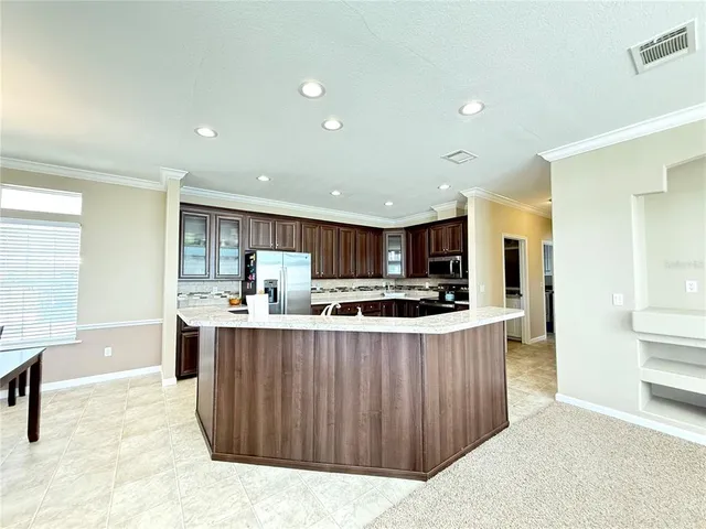 a kitchen with kitchen island a stove a refrigerator a sink dishwasher with a dining table and chairs
