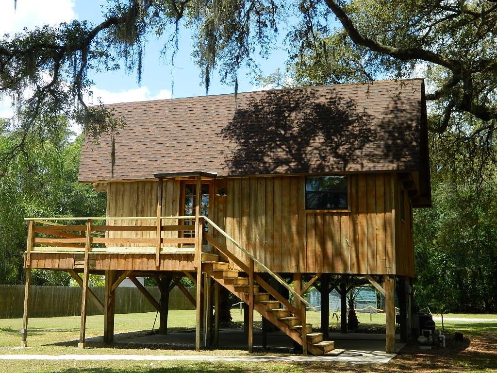 6424 Boyette Road Wesley Chapel, FL 33545 - Photo 1 of 1 a view of a roof deck with table and chairs under an umbrella with large trees