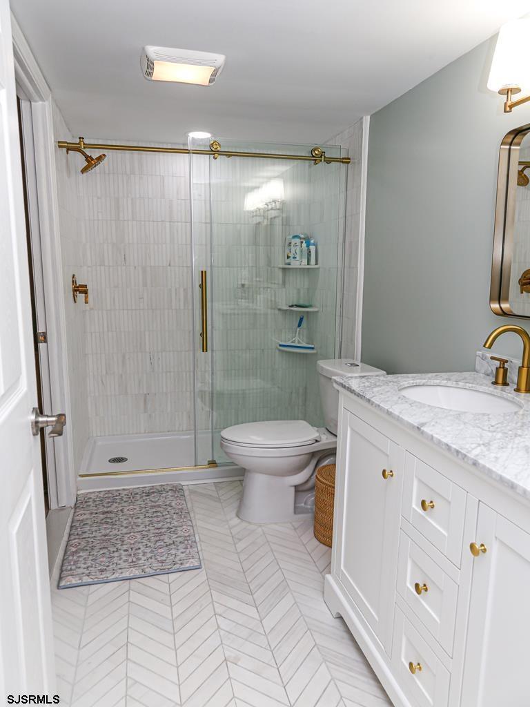 3901 Ocean Avenue, Unit 1 Brigantine, NJ 08203 - Photo 25 of 30 a bathroom with a granite countertop sink a toilet a mirror and shower