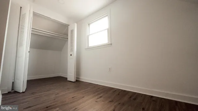 a view of an empty room with wooden floor and closet