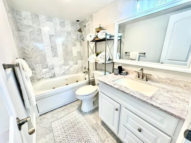 a bathroom with a granite countertop sink a toilet and bathtub