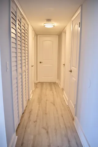 a view of a hallway with wooden floor and a bathroom