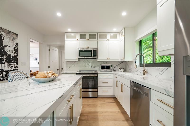 2375 Northeast 29th Street Lighthouse Point, FL 33064 - Photo 18 of 76 a kitchen with kitchen island granite countertop white cabinets and white appliances