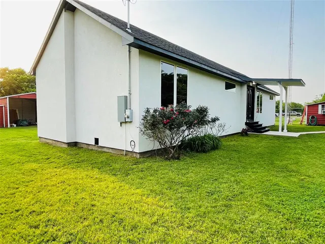 a white house that has a small yard and large trees