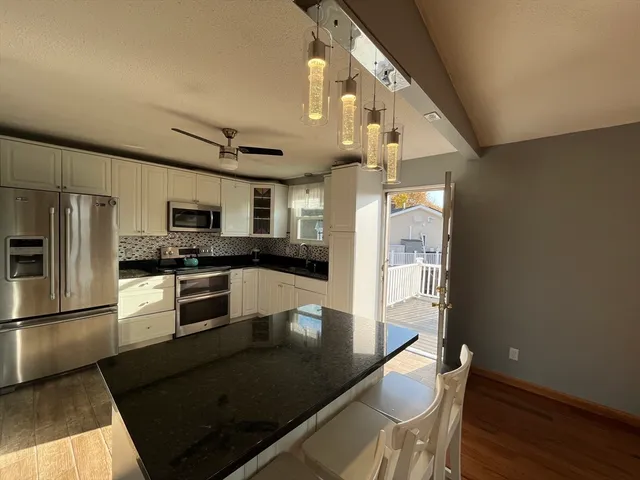 a kitchen with granite countertop a refrigerator a stove top oven and a sink