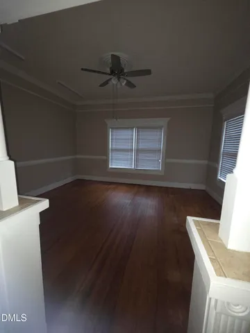 a view of a livingroom with wooden floor and a ceiling fan