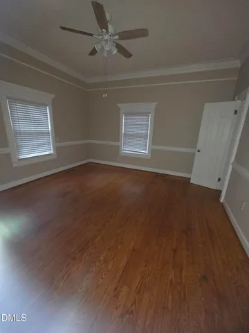 an empty room with wooden floor fan and windows