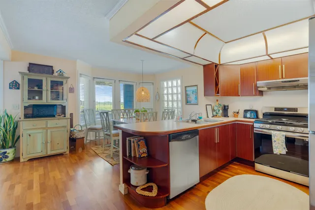 a kitchen with stainless steel appliances granite countertop a stove a sink dishwasher and a dining table with cabinets