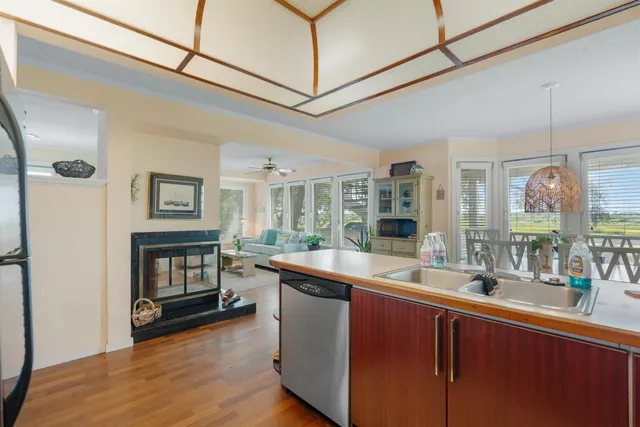a room with stainless steel appliances granite countertop a sink and wooden floors