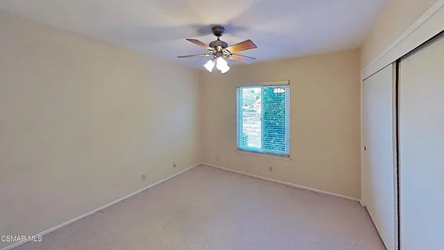 an empty room with windows and fan