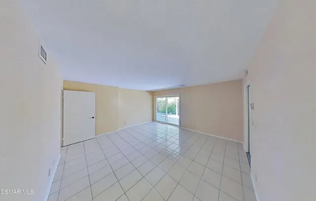 a view of an empty room with window and chandelier fan