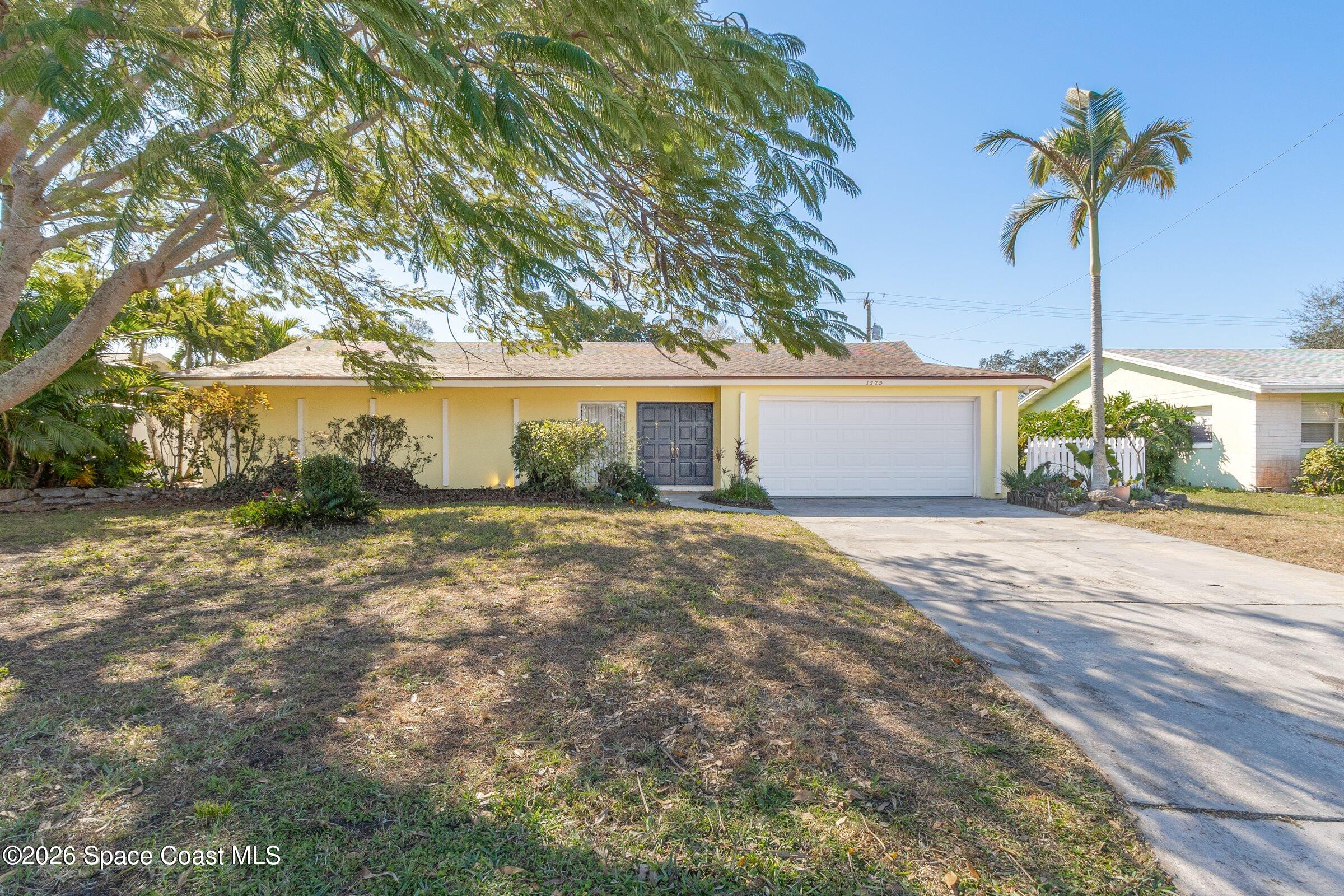 a front view of a house with a garden and tree