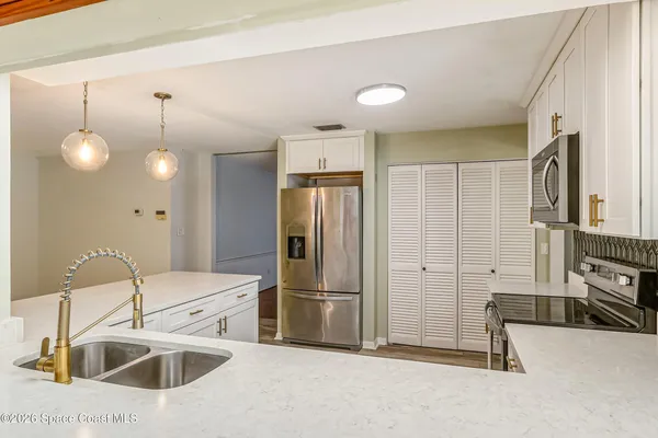 a large white kitchen with a sink a window and stainless steel appliances