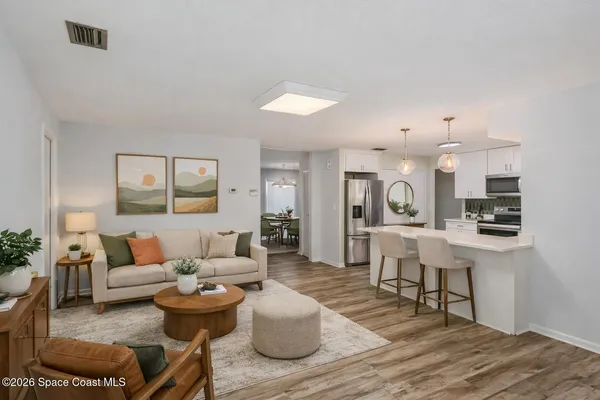 a view of an empty room with window and kitchen