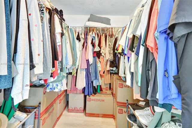 a view of walk in closet with clothes and shoes