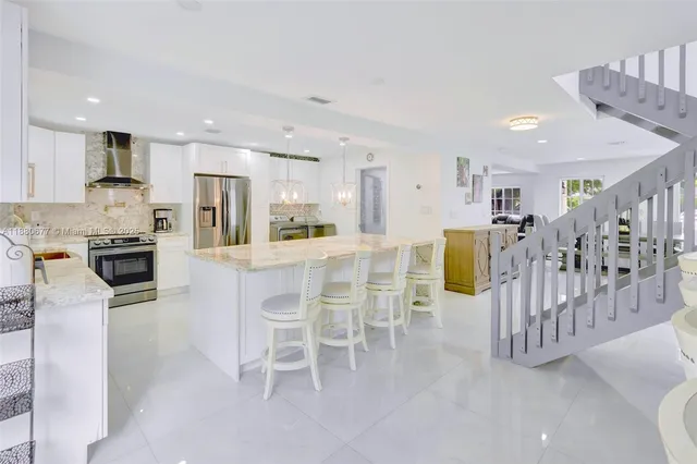 a kitchen with stainless steel appliances kitchen island granite countertop a table and chairs in it