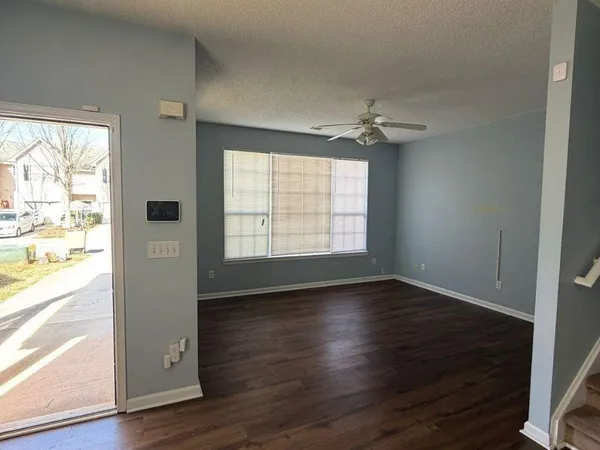 an empty room with wooden floor chandelier fan and windows