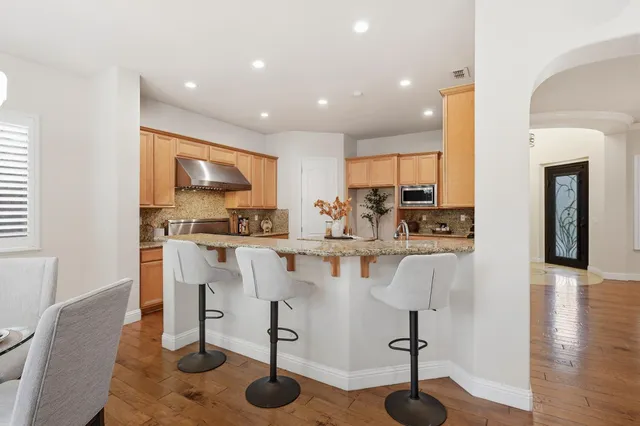 a kitchen with stainless steel appliances kitchen island granite countertop a refrigerator and cabinets