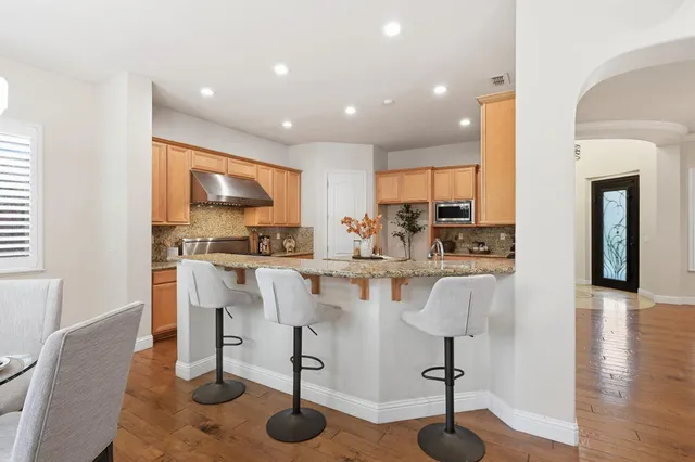 a kitchen with stainless steel appliances kitchen island granite countertop a refrigerator and a stove top oven