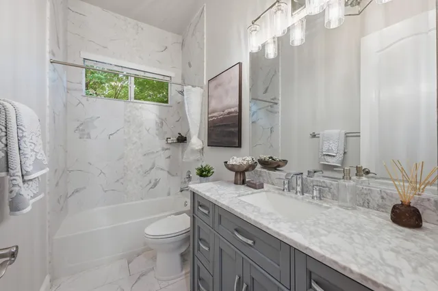 a bathroom with a granite countertop sink a toilet and shower