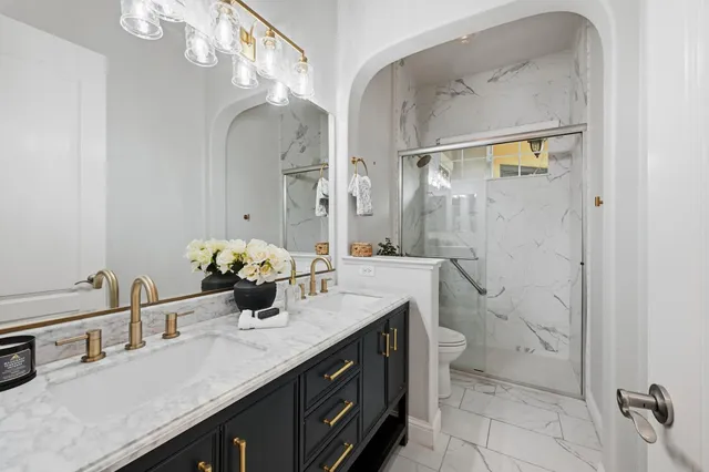 a bathroom with a granite countertop sink a toilet and shower