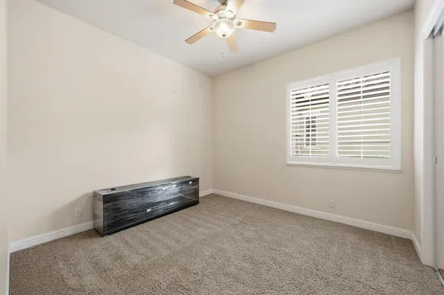 an empty room with chandelier fan and windows