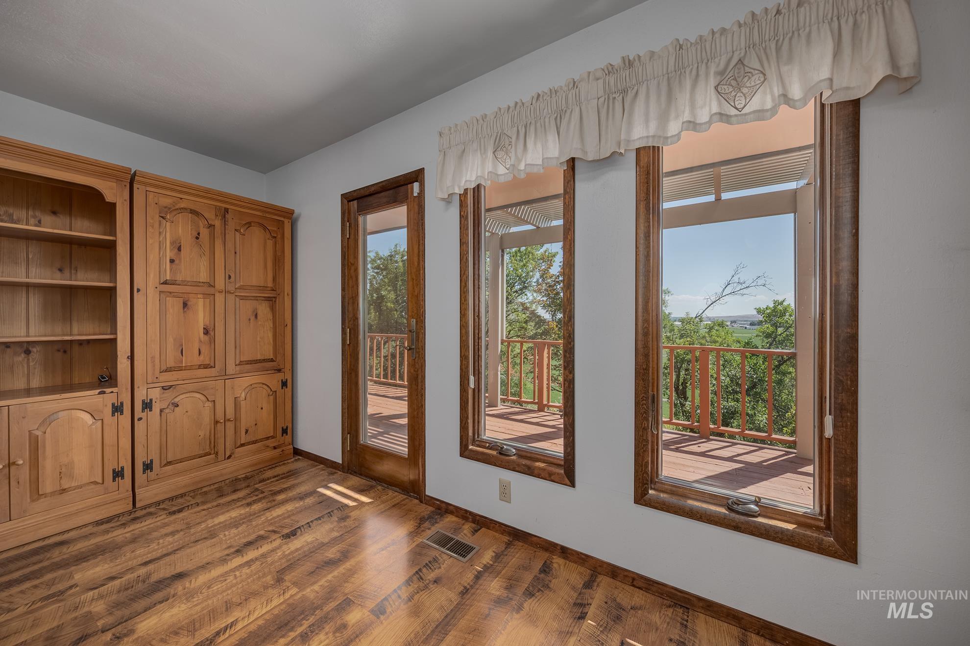 1493 Cove Road Weiser, ID 83672 - Photo 17 of 50 Room featuring wood-finish flooring, a built-in wooden cabinet with open shelving and closed storage, and a glass-paneled door