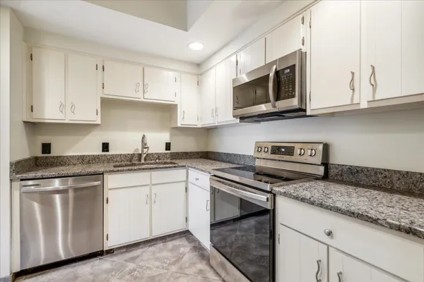 a kitchen with granite countertop white cabinets and stainless steel appliances