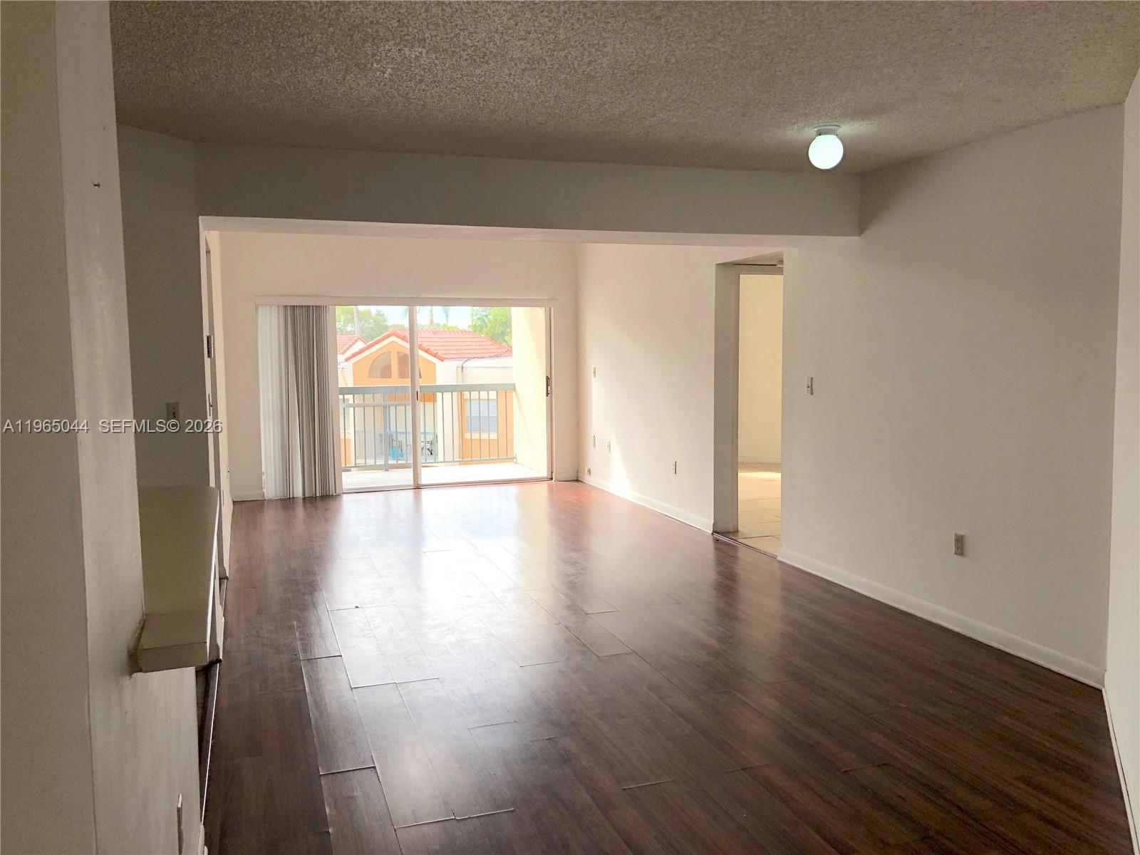 6280 Northwest 186th Street, Unit 311 Hialeah, FL 33015 - Photo 4 of 21 an empty room with wooden floor and windows with curtains