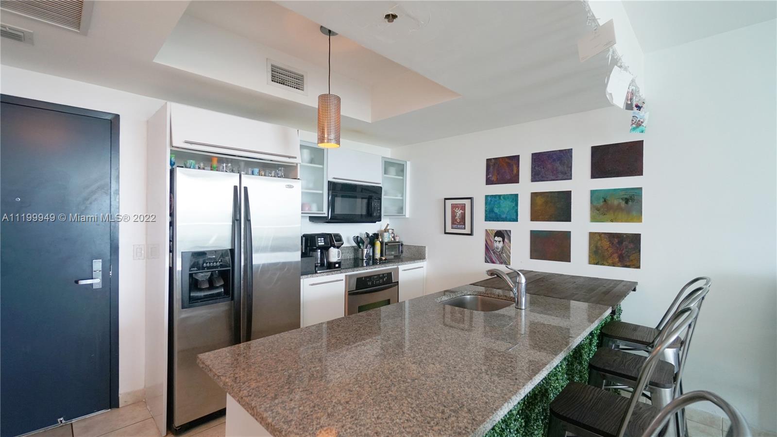 888 Biscayne Boulevard, Unit 811 Miami, FL 33132 - Photo 8 of 20 a kitchen with stainless steel appliances granite countertop a stove a refrigerator a microwave oven with a dining table and chairs