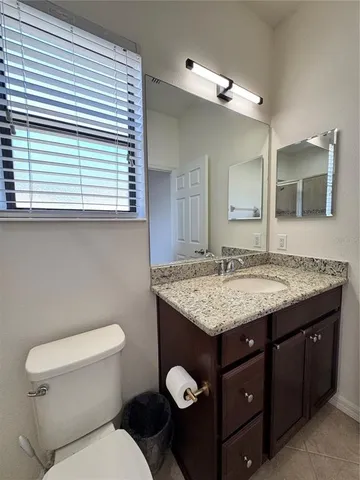 a bathroom with a granite countertop toilet sink and mirror
