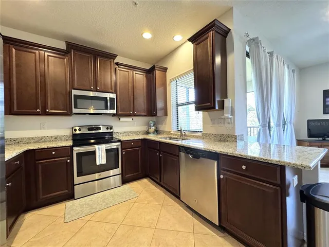 a kitchen with stainless steel appliances granite countertop wooden cabinets a stove top oven a sink and dishwasher